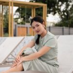 woman in gray dress shirt sitting on brown wooden picnic table during daytime